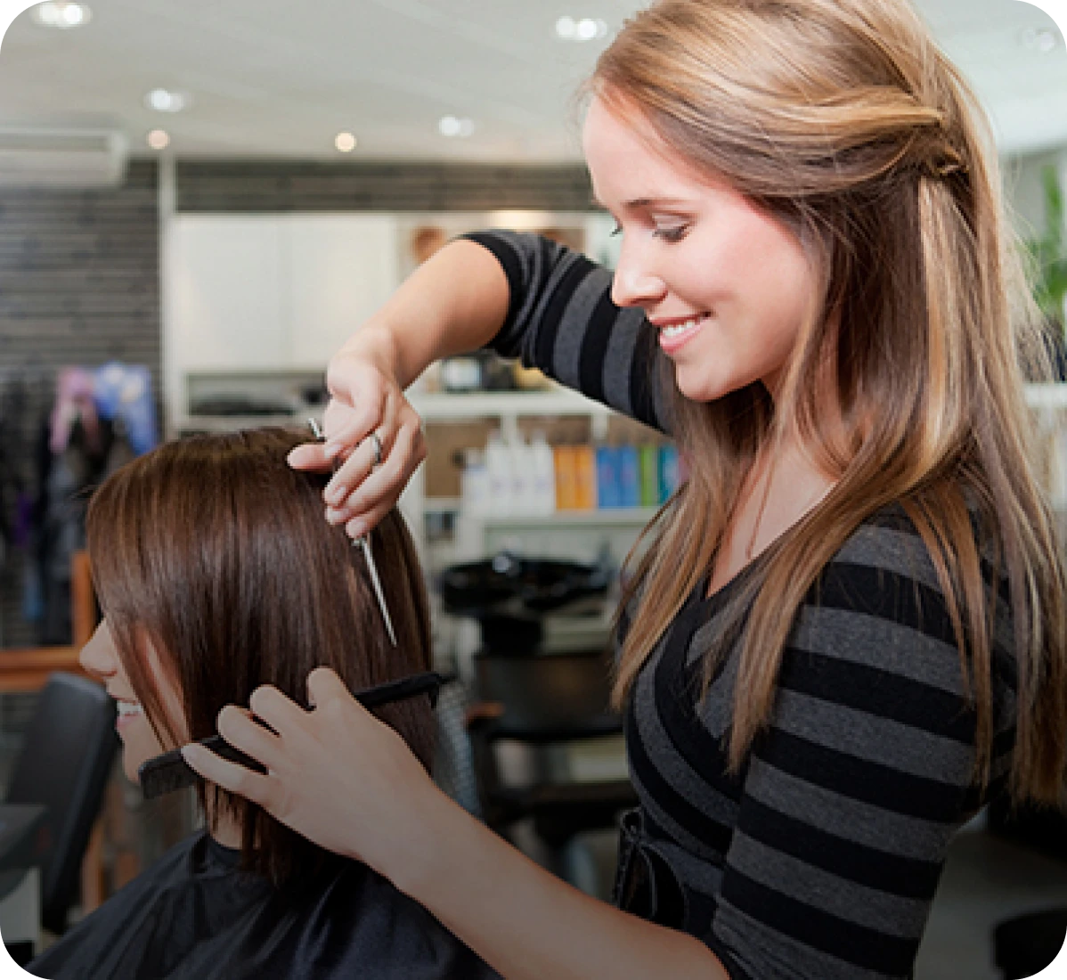 Stylist cutting woman's hair in salon.
