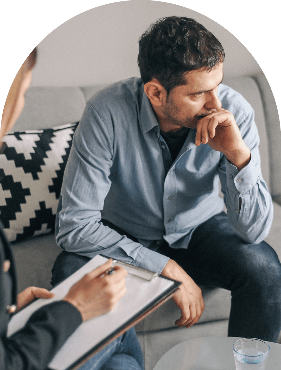 Man in therapy session, sitting pensively.