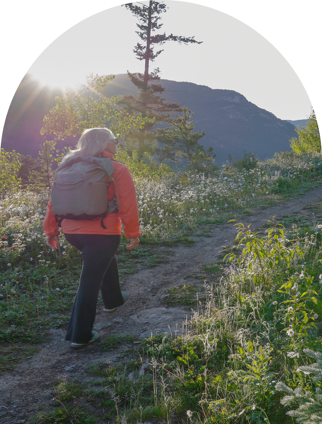 Hiker on mountain trail at sunrise.