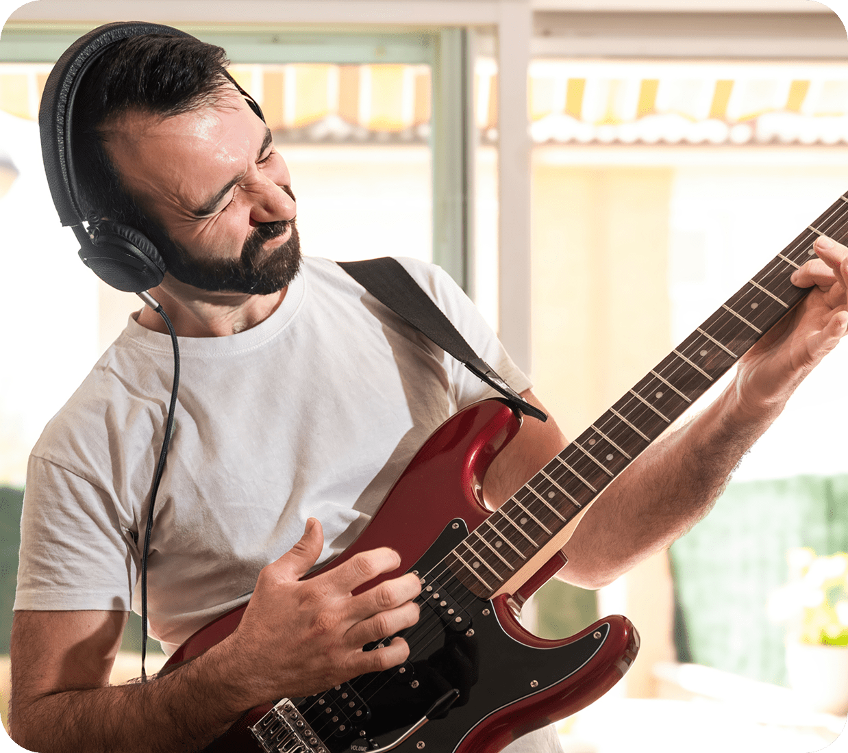 Man playing electric guitar with headphones on.