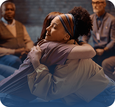 Two people embracing in a supportive setting.