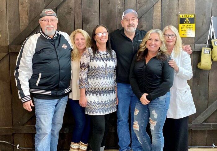 Group of six people smiling indoors.